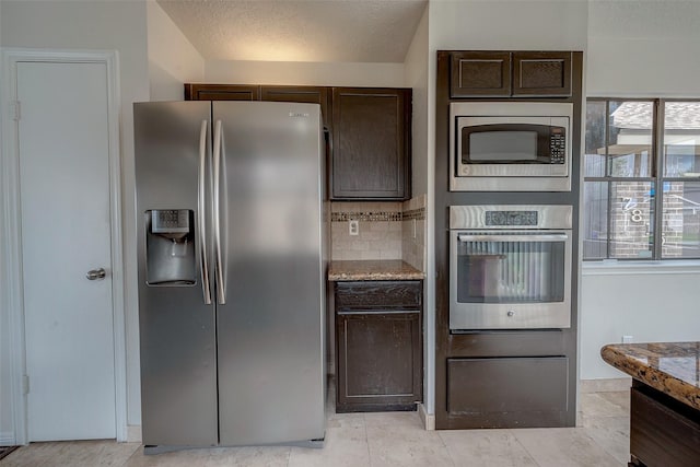 kitchen with light stone counters, dark brown cabinets, appliances with stainless steel finishes, a textured ceiling, and tasteful backsplash