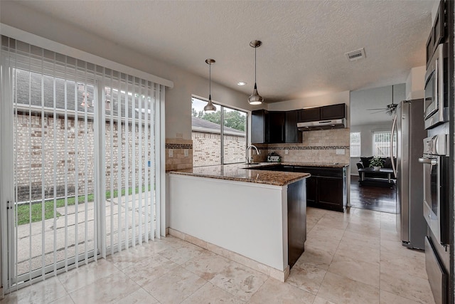 kitchen featuring visible vents, dark stone counters, a sink, appliances with stainless steel finishes, and under cabinet range hood