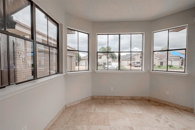 empty room featuring light tile patterned floors, a residential view, a textured ceiling, and baseboards