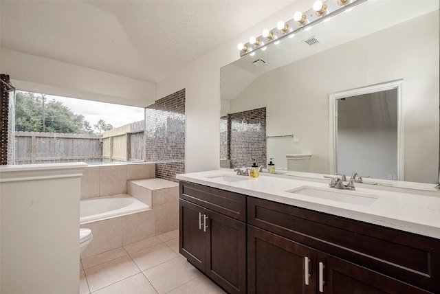 full bathroom featuring a sink, toilet, tiled bath, and tile patterned flooring