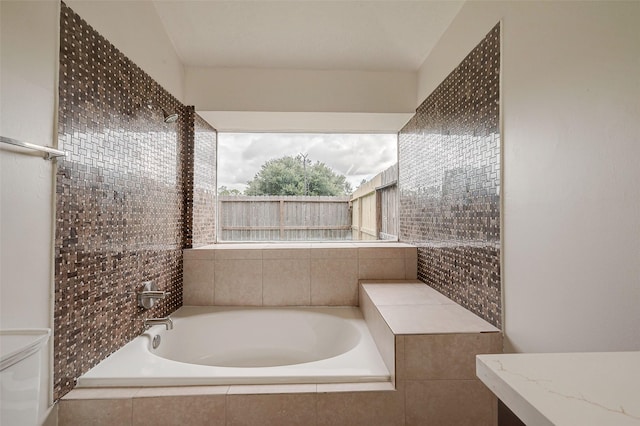 full bathroom with tiled bath and toilet