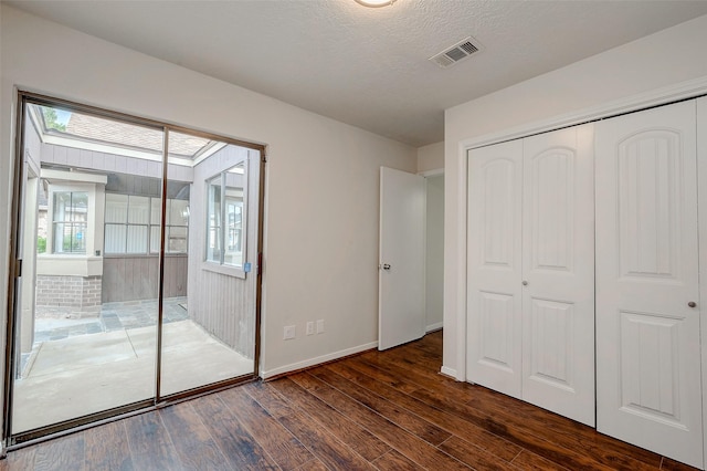 unfurnished bedroom with baseboards, visible vents, dark wood-style flooring, a closet, and a textured ceiling