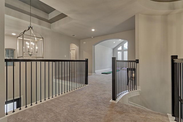 hall featuring light carpet, lofted ceiling, and a notable chandelier