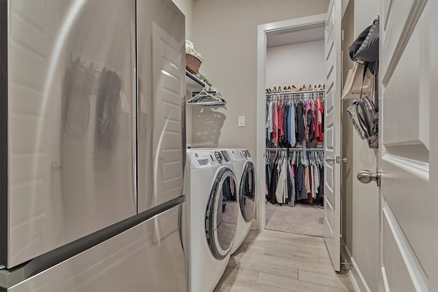 clothes washing area featuring light wood-type flooring, laundry area, and washing machine and dryer