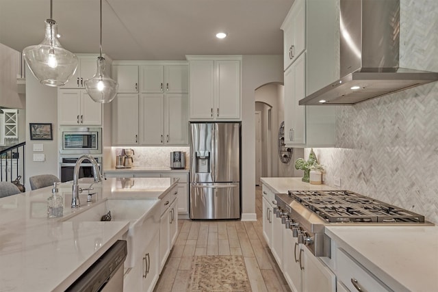 kitchen featuring white cabinets, backsplash, appliances with stainless steel finishes, and wall chimney exhaust hood