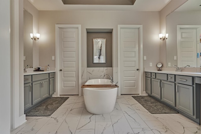 full bathroom with a freestanding bath, marble finish floor, vanity, and tile walls