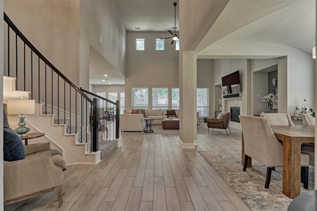 foyer featuring ceiling fan, a towering ceiling, and a stone fireplace