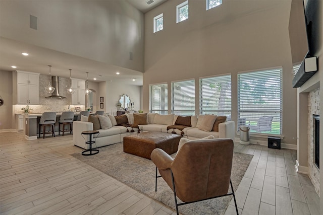 living room featuring a fireplace, a high ceiling, and light hardwood / wood-style flooring