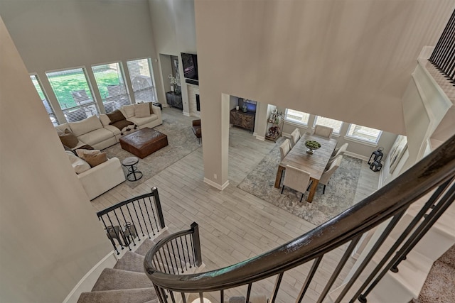 staircase featuring baseboards, a fireplace, and a high ceiling