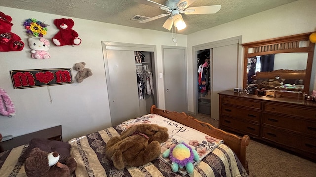 bedroom with a textured ceiling, ceiling fan, carpet, and multiple closets