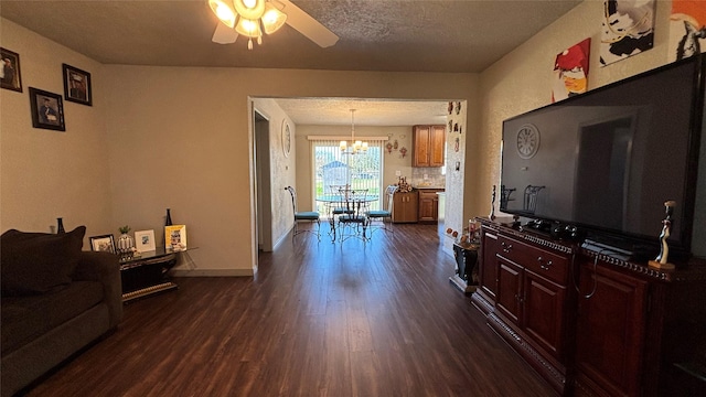 living room with dark wood-type flooring, ceiling fan with notable chandelier, and a textured ceiling