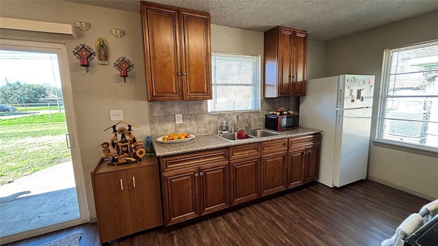 kitchen with tasteful backsplash, a wealth of natural light, sink, and white fridge