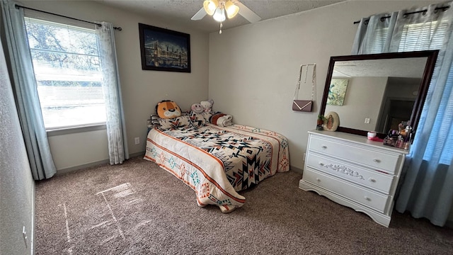 carpeted bedroom featuring ceiling fan, multiple windows, and a textured ceiling