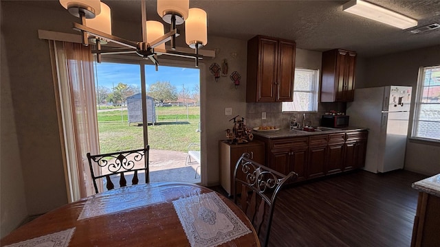 kitchen featuring white fridge, tasteful backsplash, sink, dark hardwood / wood-style floors, and a notable chandelier