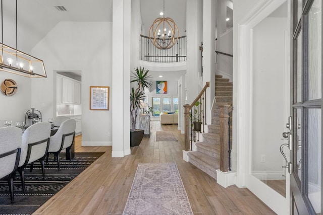 entrance foyer with high vaulted ceiling, light wood-type flooring, and a notable chandelier