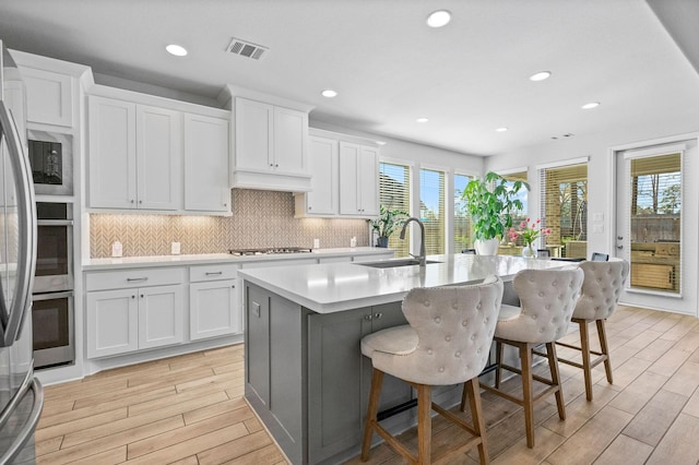 kitchen featuring white cabinets, a kitchen island with sink, and a breakfast bar