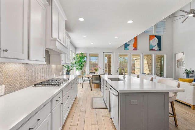 kitchen featuring a breakfast bar, a kitchen island with sink, sink, and white cabinetry