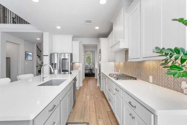 kitchen featuring a large island with sink, appliances with stainless steel finishes, sink, and white cabinetry