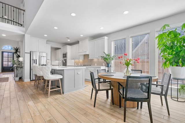 kitchen featuring decorative backsplash, white cabinets, a kitchen island with sink, and stainless steel appliances