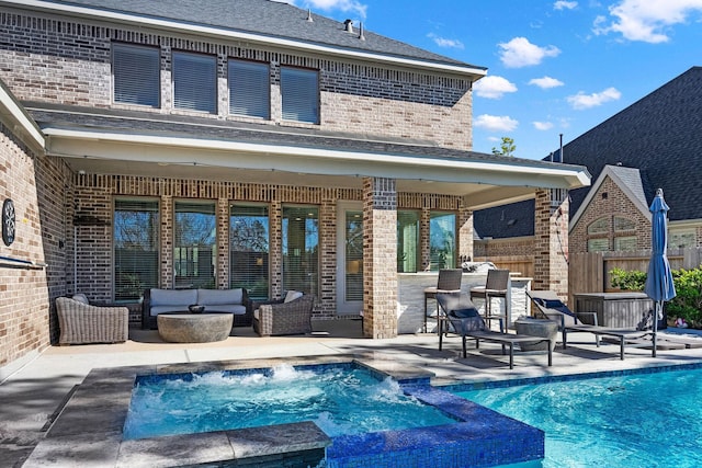 rear view of property with a swimming pool with hot tub, an outdoor hangout area, an outdoor bar, a patio, and pool water feature