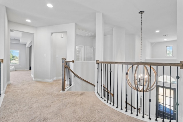 corridor featuring light colored carpet and a chandelier