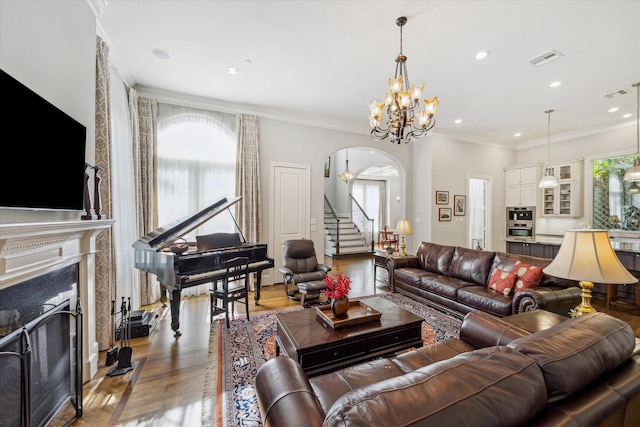 living room with arched walkways, visible vents, a premium fireplace, ornamental molding, and wood finished floors