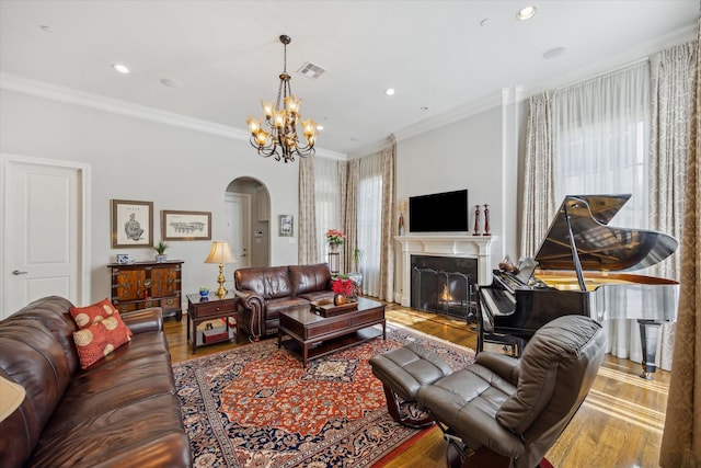 living room with wood-type flooring, a premium fireplace, crown molding, and a chandelier