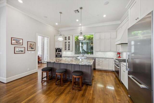 kitchen featuring a center island, white cabinetry, stainless steel appliances, decorative backsplash, and a breakfast bar area