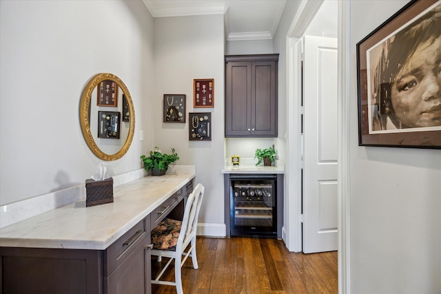 bar featuring beverage cooler, baseboards, dark wood-style floors, a bar, and crown molding