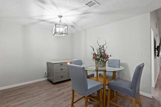 dining area with visible vents, a textured ceiling, baseboards, and wood finished floors