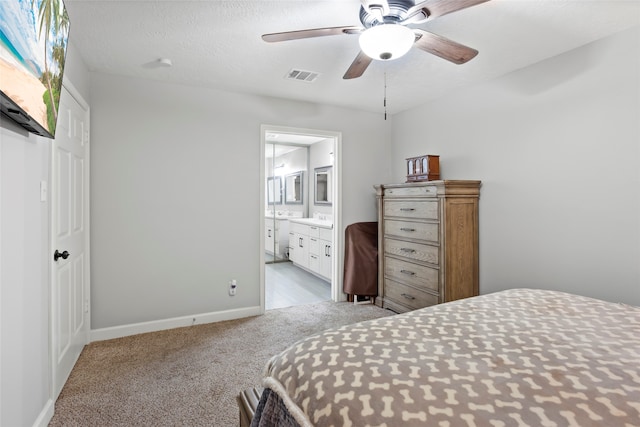 carpeted bedroom featuring visible vents, a textured ceiling, ensuite bath, baseboards, and ceiling fan