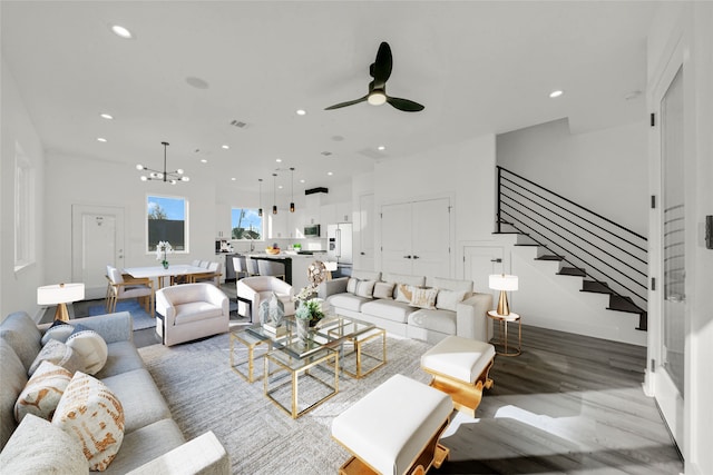 living room with ceiling fan with notable chandelier and sink