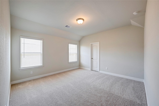 carpeted spare room featuring vaulted ceiling