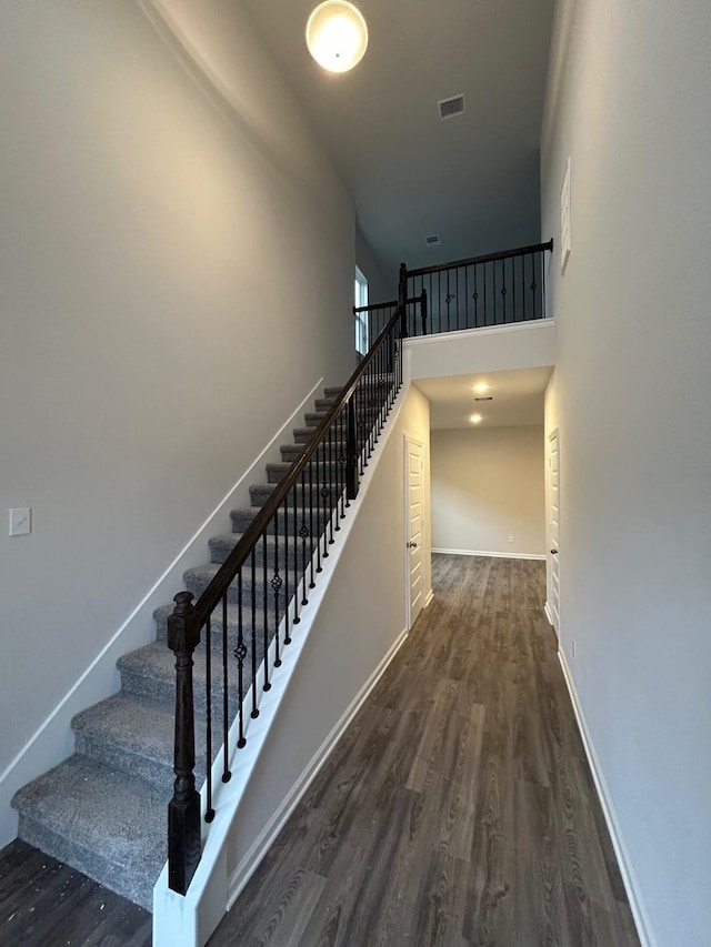 stairway with wood-type flooring and a high ceiling