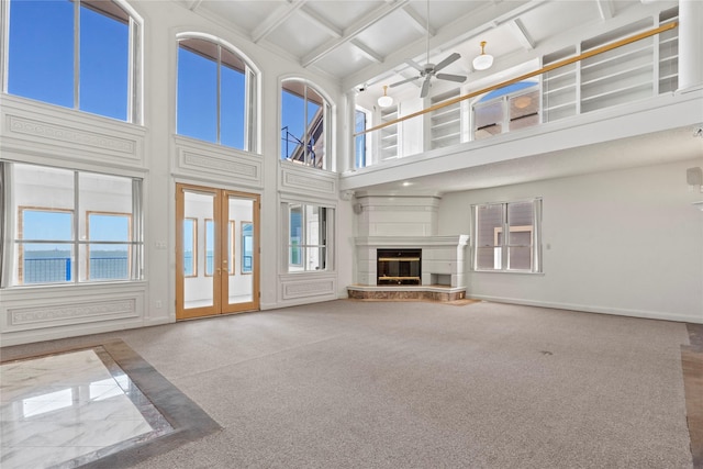 unfurnished living room with ceiling fan, a high ceiling, and coffered ceiling