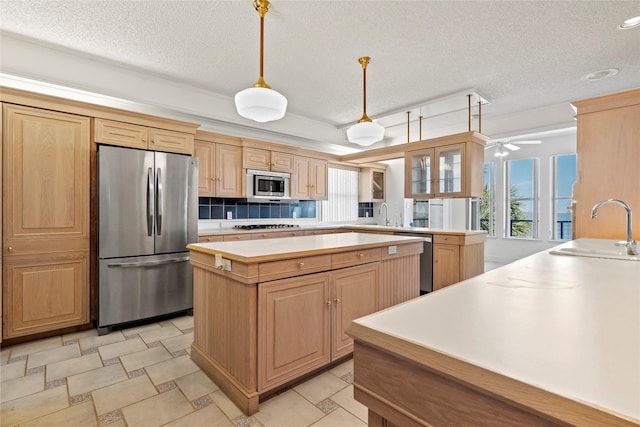 kitchen featuring pendant lighting, appliances with stainless steel finishes, tasteful backsplash, sink, and kitchen peninsula