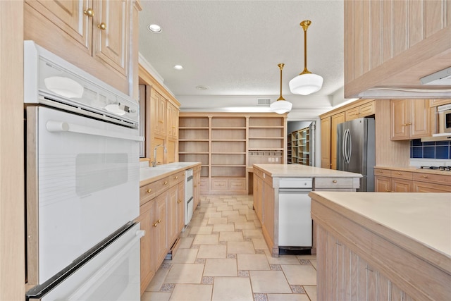 kitchen featuring pendant lighting, appliances with stainless steel finishes, a textured ceiling, light brown cabinets, and sink