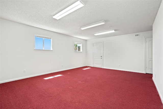 spare room with a textured ceiling and dark colored carpet