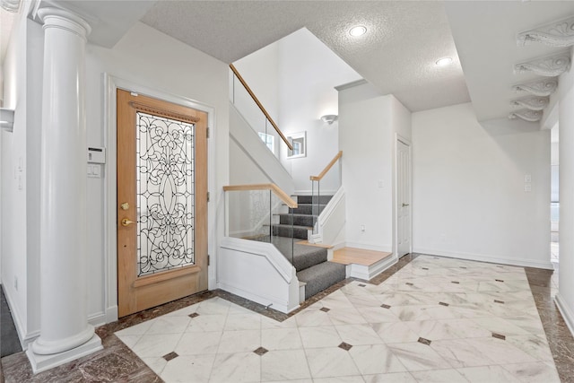 foyer entrance featuring decorative columns and a textured ceiling