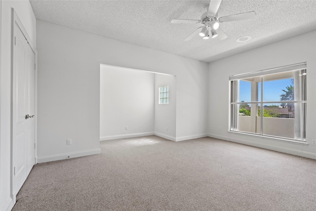 spare room with ceiling fan, a textured ceiling, and carpet flooring