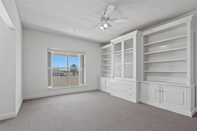 empty room with a textured ceiling, ceiling fan, and light colored carpet