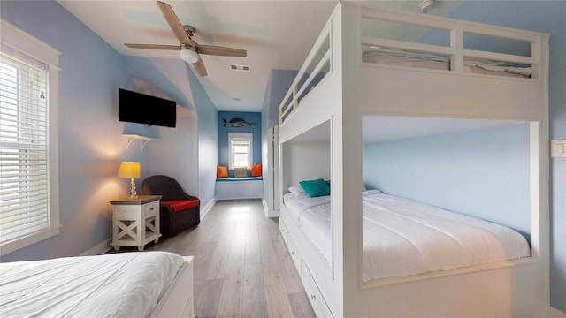 bedroom with ceiling fan, multiple windows, and light hardwood / wood-style flooring