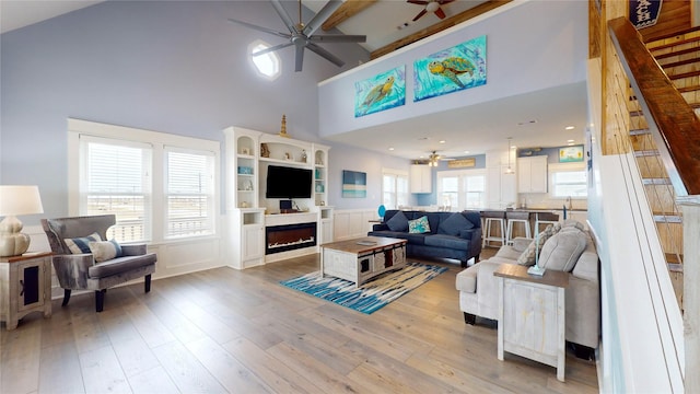 living room featuring beamed ceiling, light hardwood / wood-style floors, plenty of natural light, and high vaulted ceiling