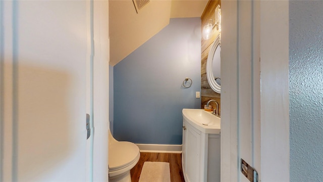 bathroom with toilet, vanity, and wood-type flooring