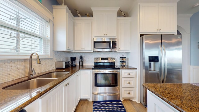 kitchen with sink, white cabinets, stainless steel appliances, and dark stone counters