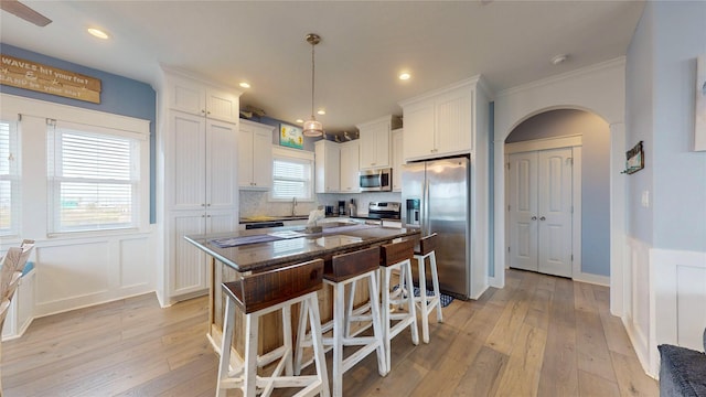 kitchen featuring appliances with stainless steel finishes, white cabinets, hanging light fixtures, and a center island