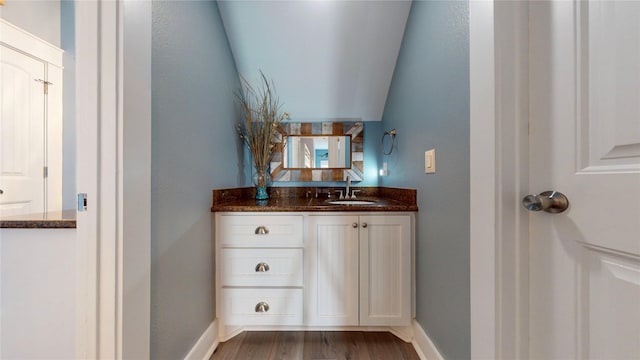 bathroom with hardwood / wood-style floors, vanity, and lofted ceiling