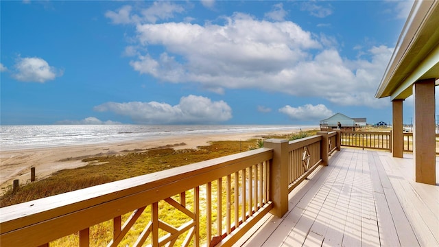 wooden deck with a water view and a beach view