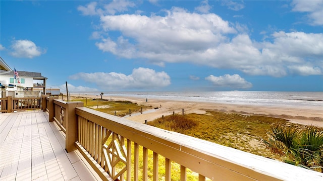 wooden terrace with a water view and a view of the beach