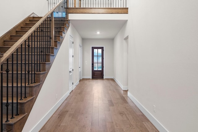 entryway with wood-type flooring and a towering ceiling